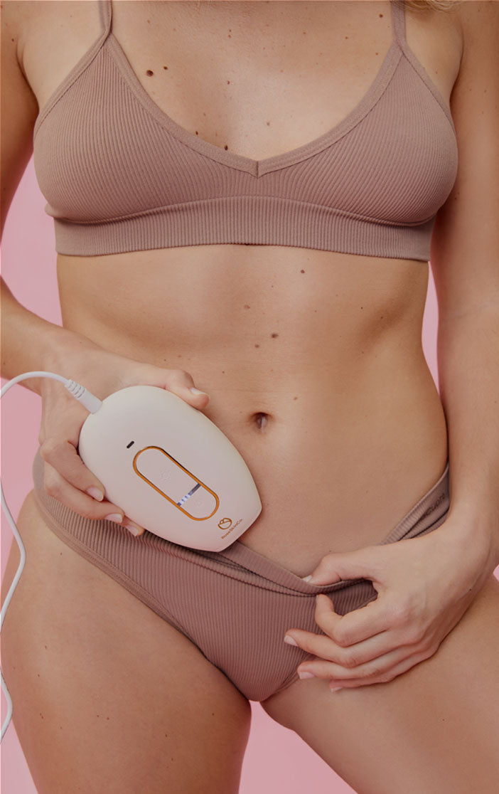 Woman holding Lumi Permanent Hair Removal Device near her bikini area